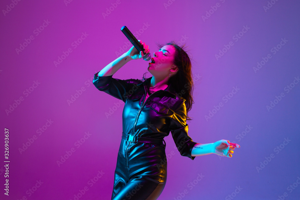 Caucasian female singer portrait isolated on purple studio background
