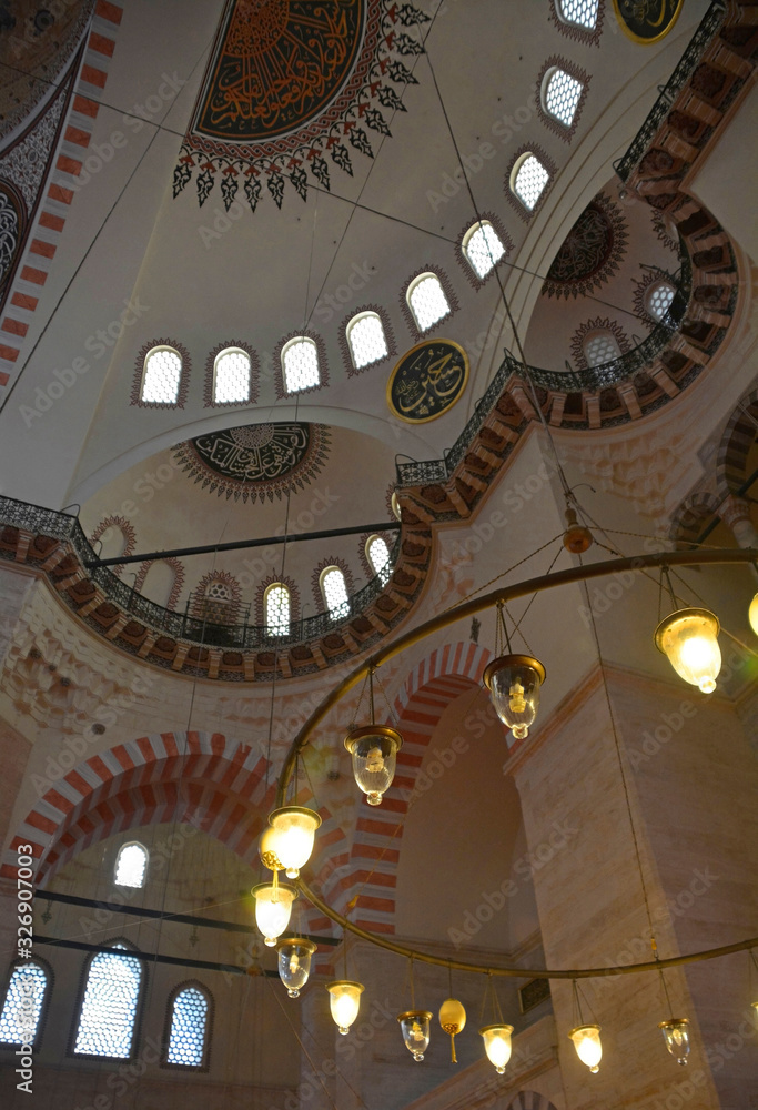Fototapeta premium The interior of the 16th century Suleymaniye mosque, the largest Ottoman mosque in Istanbul, Turkey. Focus on the foreground lights