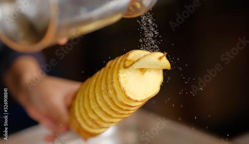 tornado potatoe on a stick being salted