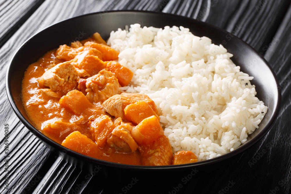 African stew Domoda with peanuts cooked with chicken pumpkin and served with rice close-up in a plate. horizontal. African stew Domoda with peanuts cooked with chicken pumpkin and served with rice close-up in a plate. horizontal.