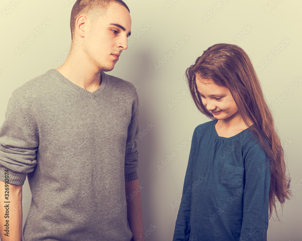 Young serious teen father have a dialog with his small school girl daughter. Happy joyful emotions on toned vintage color background. Young serious teen father have a dialog with his small school girl daughter. Happy joyful emotions on toned vintage color background.