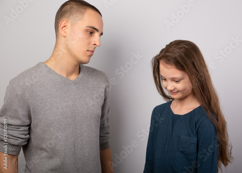 Young serious teen father have a dialog with his small school girl daughter. Happy joyful emotions on toned vintage color background.