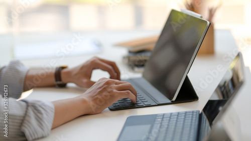 Side view of entrepreneur working on digital tablets on white table  in modern workplace © bongkarn