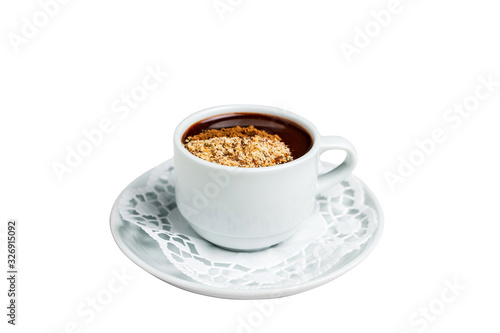 A small white cup of dark hot chocolate with nutmeg and cinnamon on a white saucer and a napkin