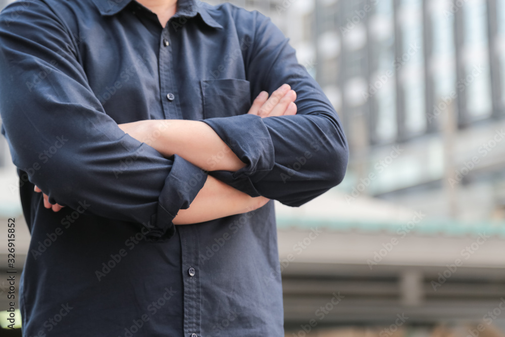 Confident male business executive with arms crossed standing in front of office building Confident male business executive with arms crossed standing in front of office building