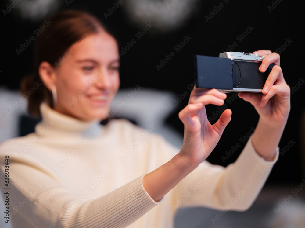 Cute millennial woman or girl makes selfie on mirrorless camera to share on internet social media channels
