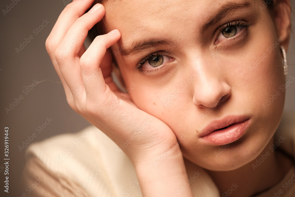A close-up portrait of a beautiful young girl with brown hair and green eyes with natural makeup in light clothing A close-up portrait of a beautiful young girl with brown hair and green eyes with natural makeup in light clothing