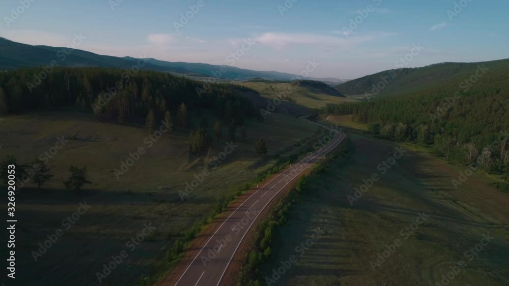 AERIAL, TOP DOWN: Dark colored car driving down an asphalt road crossing the vast forest on a sunny summer day. AERIAL, TOP DOWN: Dark colored car driving down an asphalt road crossing the vast forest on a sunny summer day.