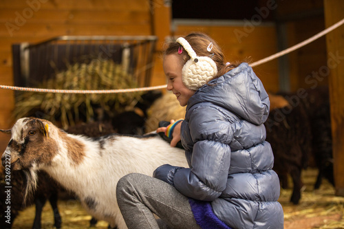 Little girl petting friendly goat at zoo