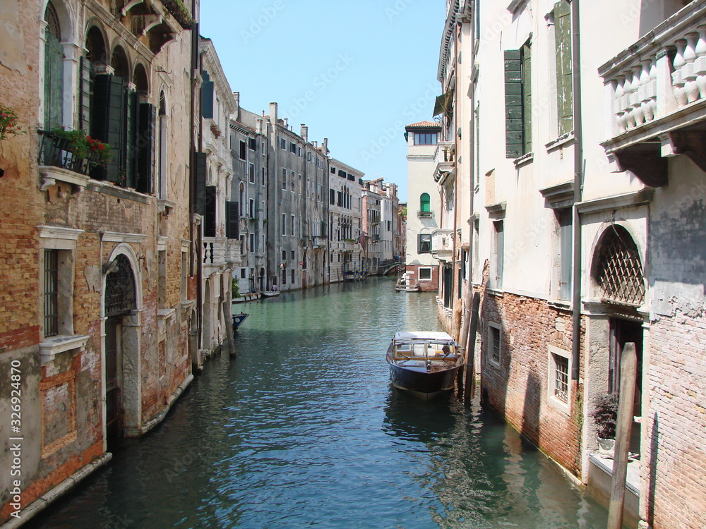 The unique landscape of the narrow waterways of sunny Venice, connected by small numerous bridges.