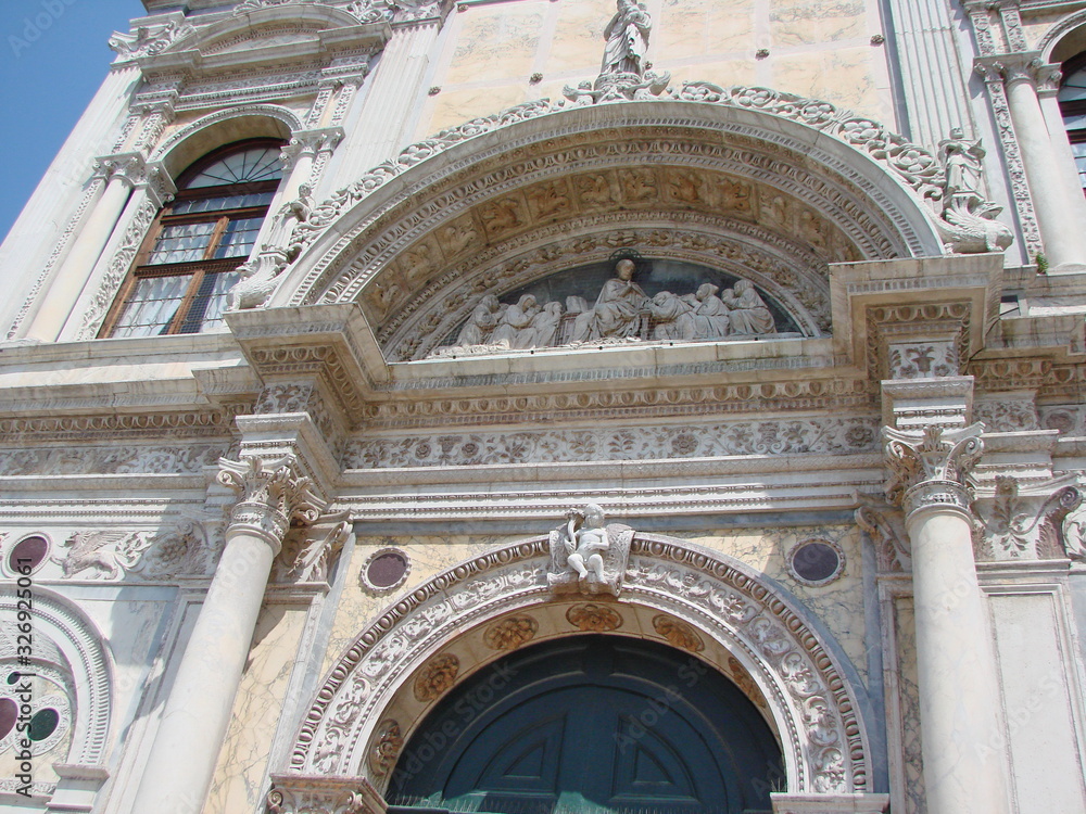 Bottom view of the architectural grandeur of the amazing beauty of the sculptural compositions of Venetian temples and cathedrals in the middle of a summer sunny day.