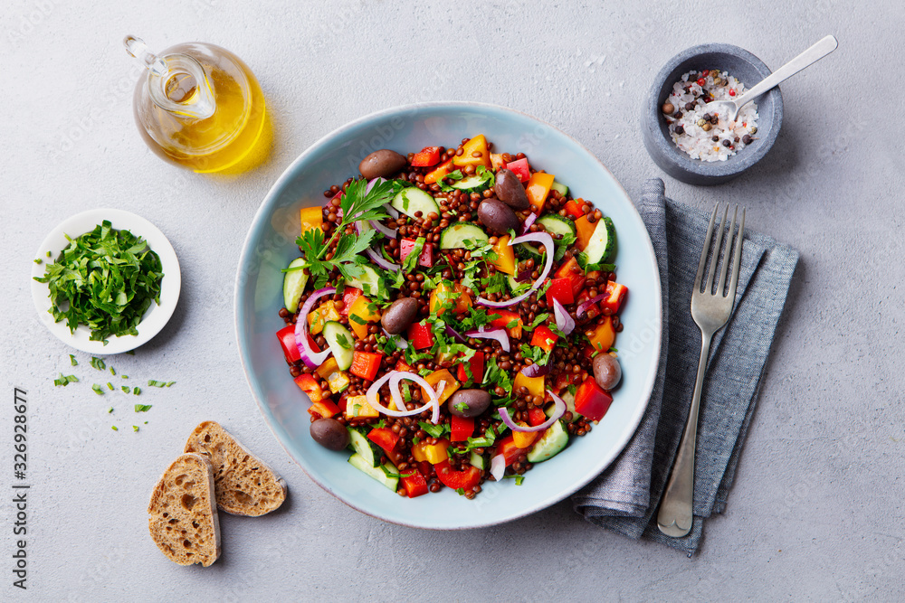 Lentil salad with mix vegetables in bowl. Grey background. Top view.