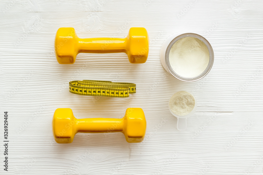Sport diet. Protein shake near dumbbells on white background top-down flat lay Sport diet. Protein shake near dumbbells on white background top-down flat lay