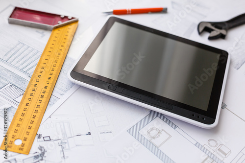 High angle view of tablet PC with blueprint and model structure on table