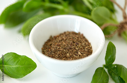 greens, culinary and flavoring concept - bunch of fresh basil herb and dry seasoning in cup on white background