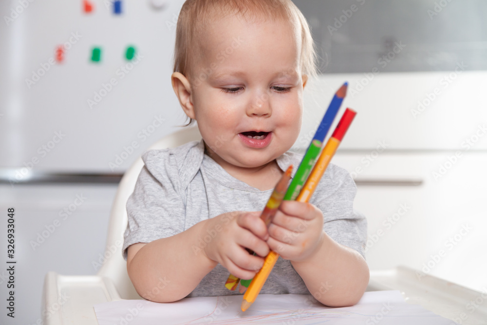 Cute baby paint using colorful pencils on white table Cute baby paint using colorful pencils on white table