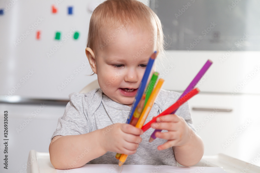 Cute baby paint using colorful pencils on white table Cute baby paint using colorful pencils on white table