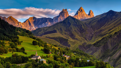 Foto auf Acrylglas Alpen Kirche in einem Dorf in den französischen Alpen mit 3000 Meter hohen Bergen. Grüne Wiesen im Frühling  © Creative Clicks