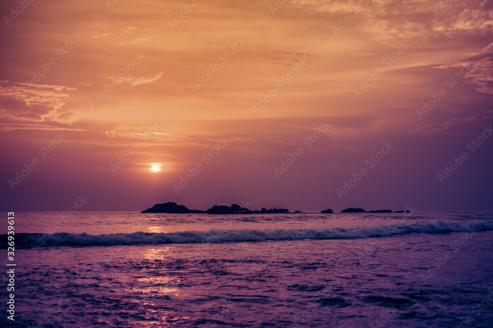 Obraz premium Beautiful orange sun at sunset and a path of light on the waters of the Indian Ocean