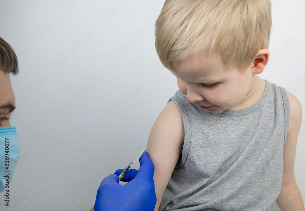 A doctor injects a vaccine into the boy’s shoulder. The concept of vaccination of children and the prevention of infectious diseases. A doctor injects a vaccine into the boy’s shoulder. The concept of vaccination of children and the prevention of infectious diseases.