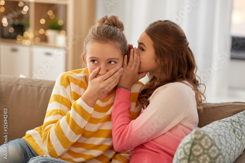 people, friendship and secret concept - teenage girls gossiping at home