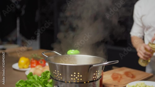 Unrecognizable chef pouring olive oil on freshly boiled pasta and tossing pasta in colander to mix with oil photo