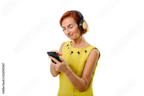 Elderly redhead woman in earphones holding smartphone photo