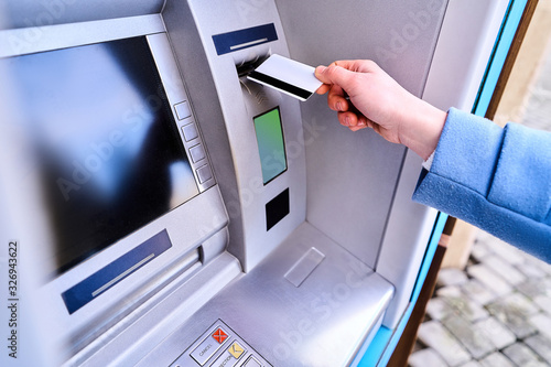 Person insert plastic credit card into street atm bank to withdrawing money photo