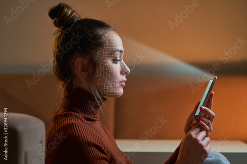 Female scans face using facial recognition system on smartphone for biometric identification. Future digital high tech technology and face id photo