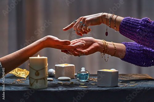 Magic gypsy woman reading palm lines around candles and other magical accessories. Witch during fortune telling palmistry, prediction the future life and divination ritual