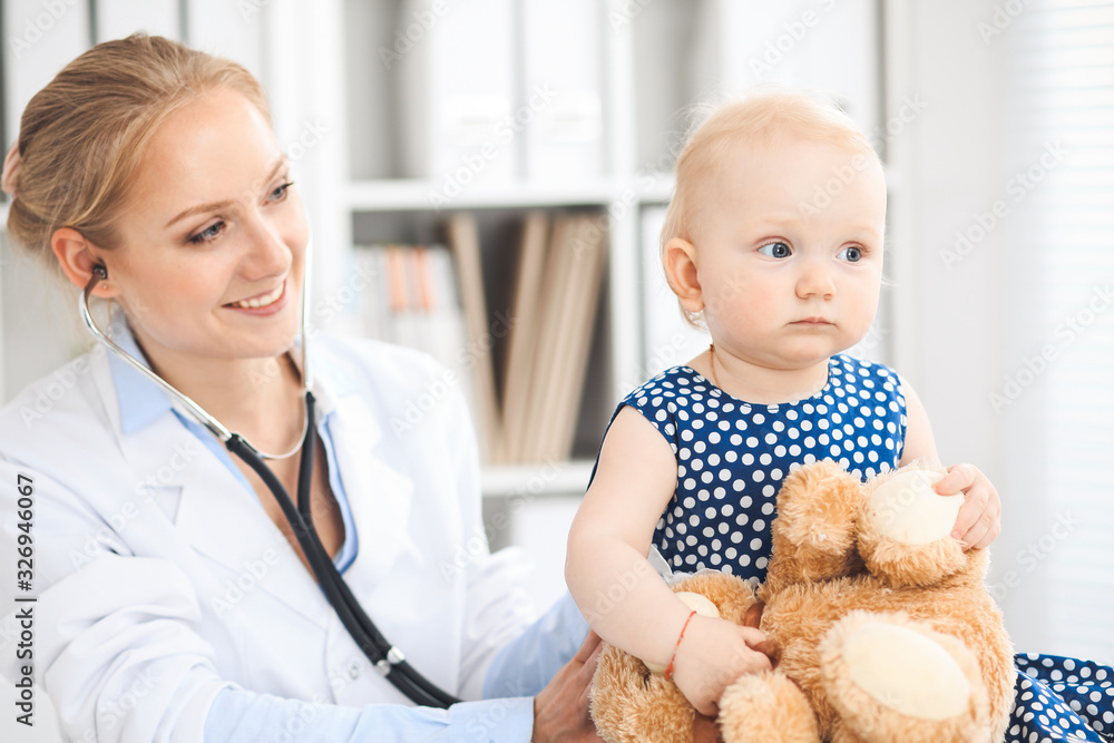 Doctor and patient in hospital. Little girl dressed in dark blue dress is being examined by doctor with stethoscope. Medicine and healthcare concept Doctor and patient in hospital. Little girl dressed in dark blue dress is being examined by doctor with stethoscope. Medicine and healthcare concept