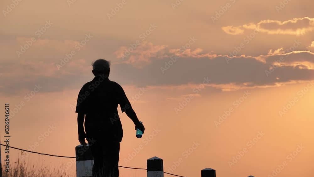 Rear view Asian elderly exercise. Senior man walking on road In the morning with the sunrise behind Slow Motion. health lifestyle and exercise Concept Rear view Asian elderly exercise. Senior man walking on road In the morning with the sunrise behind Slow Motion. health lifestyle and exercise Concept