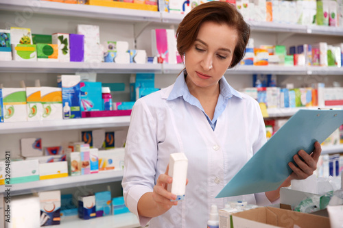 Professional pharmacist with clipboard and medicine in drugstore