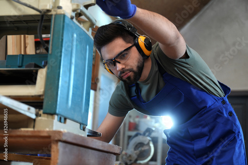 Slika na platnu Professional carpenter working with grinding machine in shop
