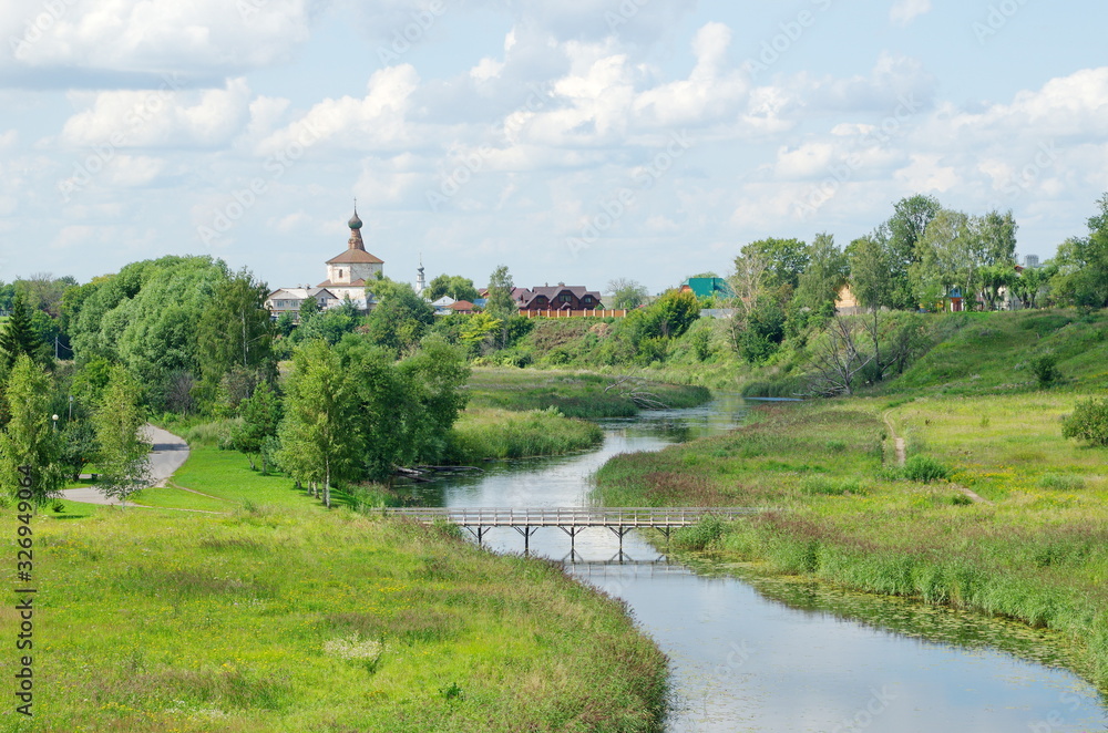 Summer landscape with views of the Kamenka river and the Church of Kosma and Damian in Korovniki. City of Suzdal. Golden ring of Russia