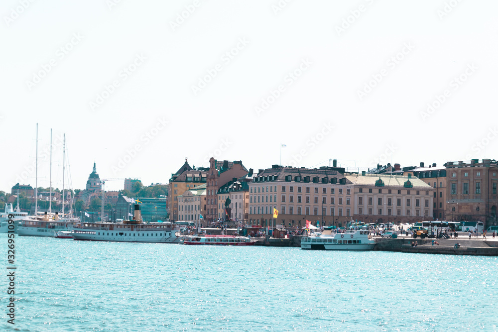 Naklejka premium Stockholm, Sweden June 7 2019: Beautiful panorama of the promenade in Stockholm, Sweden. The delightful architecture of the houses. Big and small boats, ships stand at the pier on a sunny day