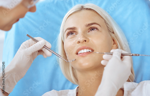 Smiling blonde woman examined by dentist at dental clinic. Healthy teeth and medicine concept