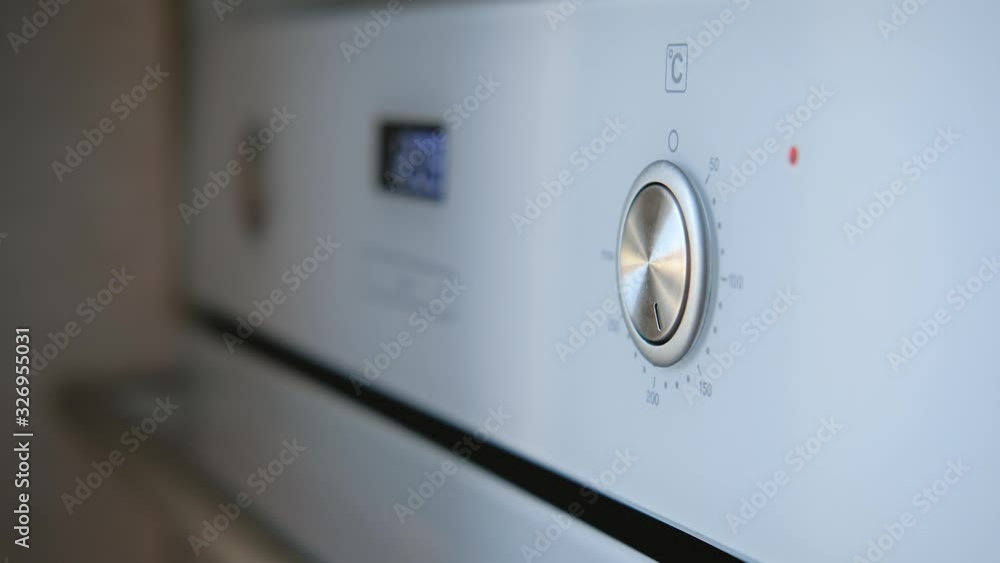 Closeup of female hand turns the oven switch sets temperature Closeup of female hand turns the oven switch sets temperature