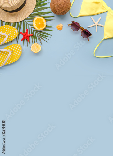 Vertical Summer beach flat lay background with copy space. Top view bikini, palm leaf ant hat on a blue background