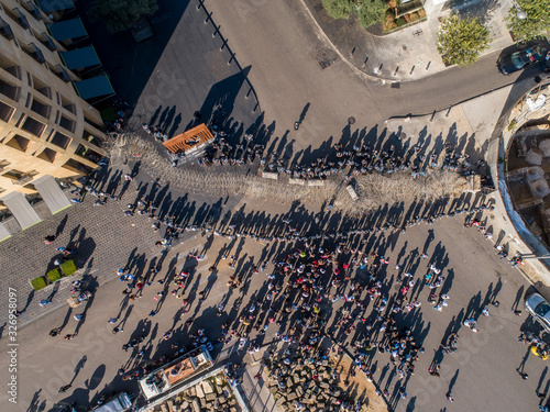 Beirut, Lebanon 2019: Aerial top view drone shot of numerous protesters at Martyrs' Square facing the police and wires blocking the road during the Lebanese Revolution.