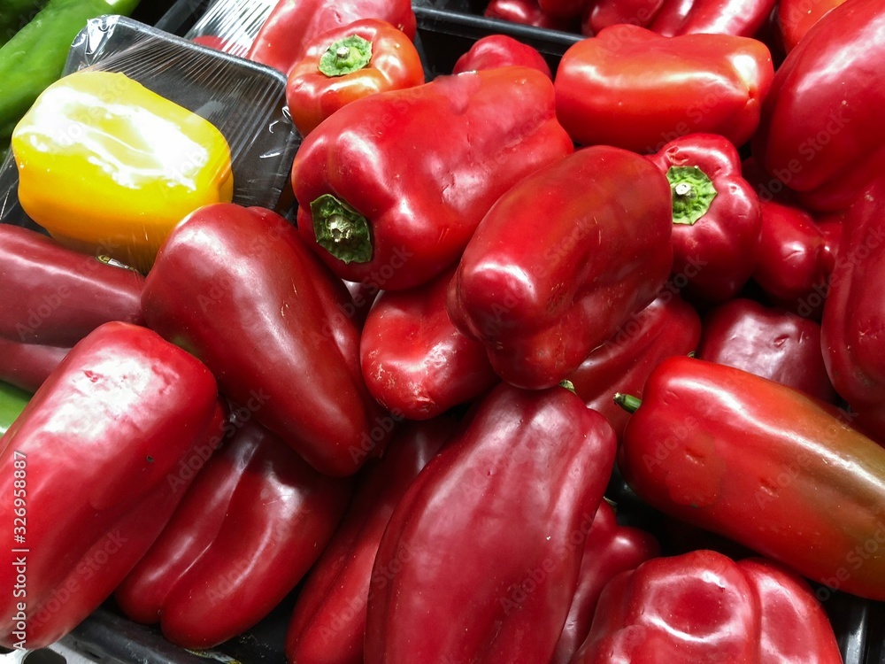 Close up of red and yellow bell peppers at the fresh produce section of a grocery store. Close up of red and yellow bell peppers at the fresh produce section of a grocery store.