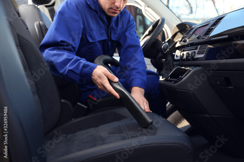 Car wash worker vacuuming automobile seat, closeup