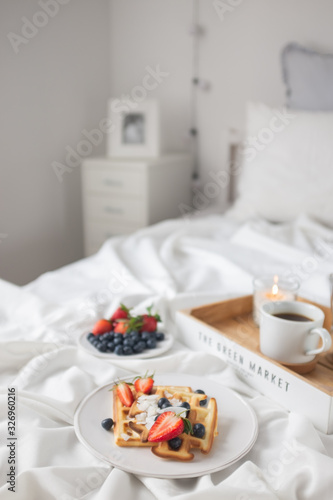 Beautiful breakfast in bed: Viennese Belgian waffles decorated with berries, a plate with strawberries and blueberries