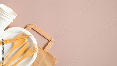 Eco store banner design template. Empty kraft paper bag and eco-friendly cutlery set on brown background. Flat lay, top view. Sustainable lifestyle. Zero waste, plastic free concept