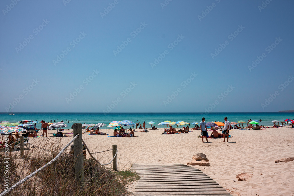 A wooden walkway leads to a sandy beach in Formentera in the Balearic islands of Spain.