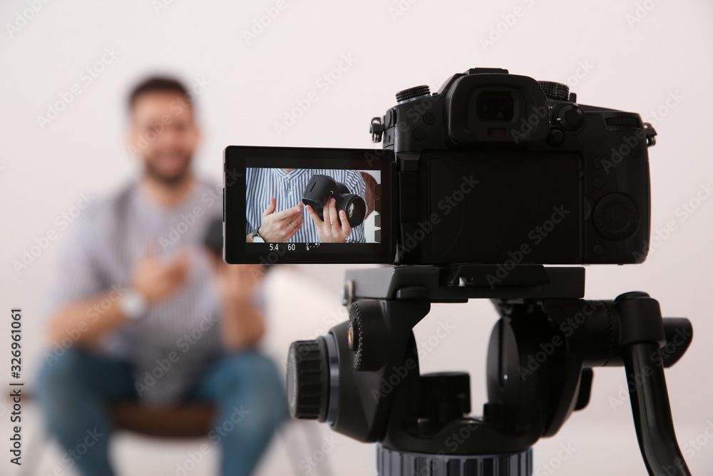 Young blogger with camera recording video indoors, focus on screen
