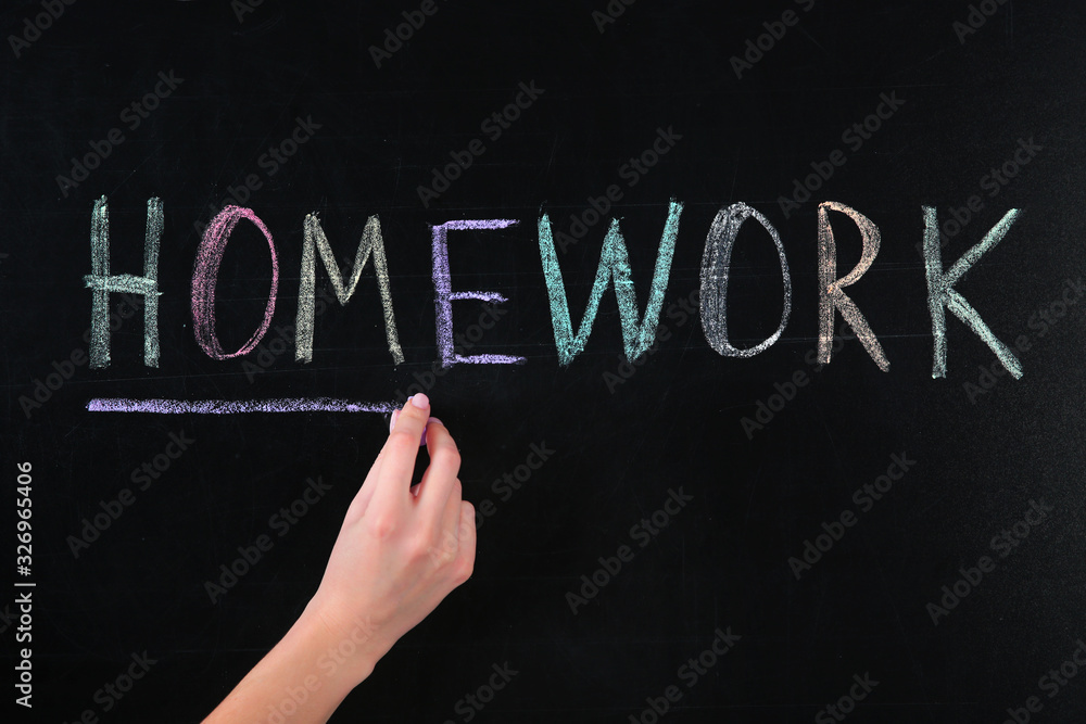 Woman writing word HOMEWORK on chalkboard, closeup Woman writing word HOMEWORK on chalkboard, closeup