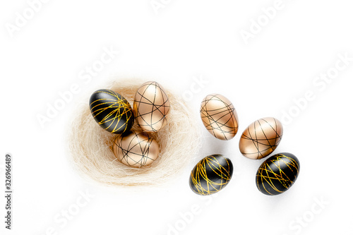 Easter golden decorated eggs in nest on white background . Minimal easter concept copy space for text. Top horizontal view, flatlay.
