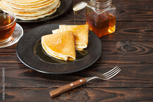 puncakes with honey and cup of tea on old wooden background photo