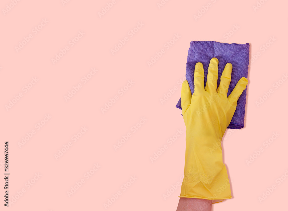 A man's hand in a rubber glove holds a blue rag on a red background. Cleaning. Cozy house. Space for text. A man's hand in a rubber glove holds a blue rag on a red background. Cleaning. Cozy house. Space for text.